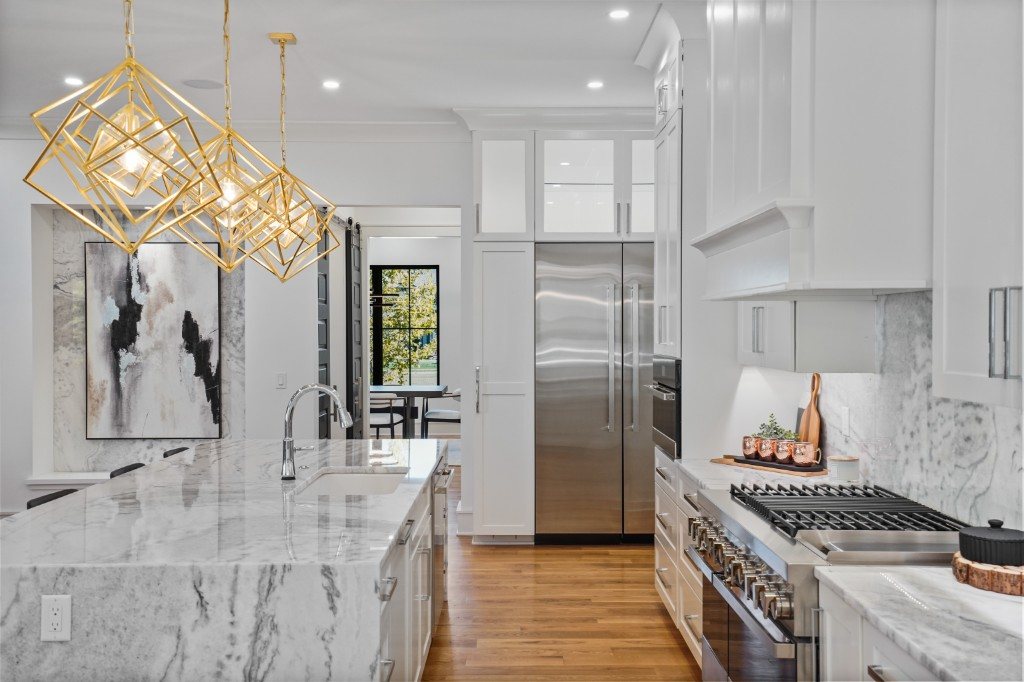 Chef's kitchen with marble island and gold geometric pendants