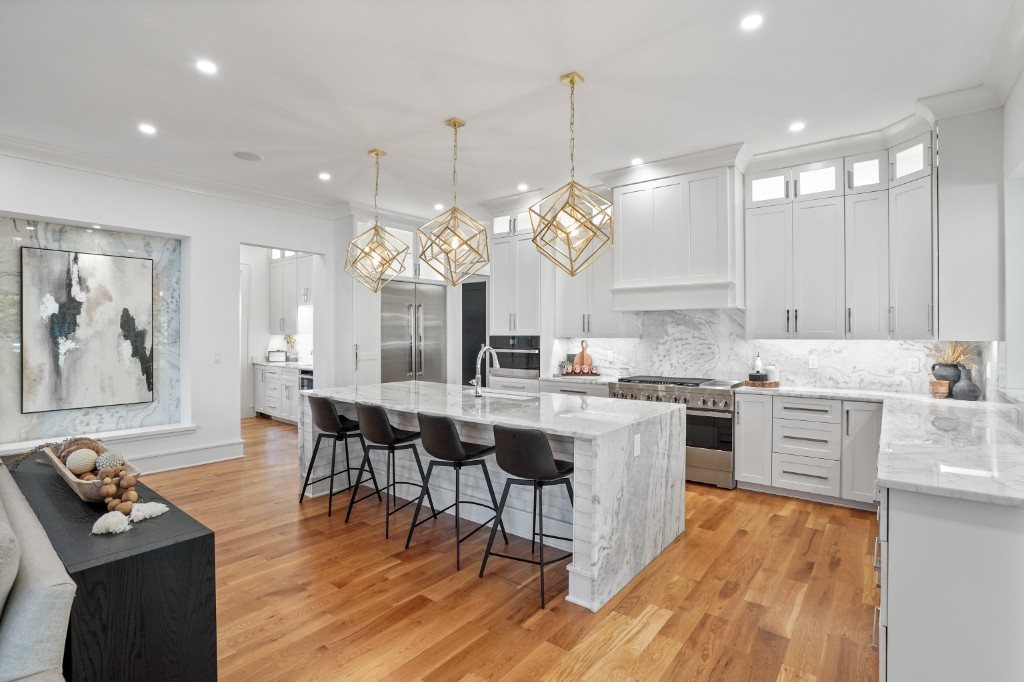 Kitchen view with marble waterfall island, gold pendants, and professional range